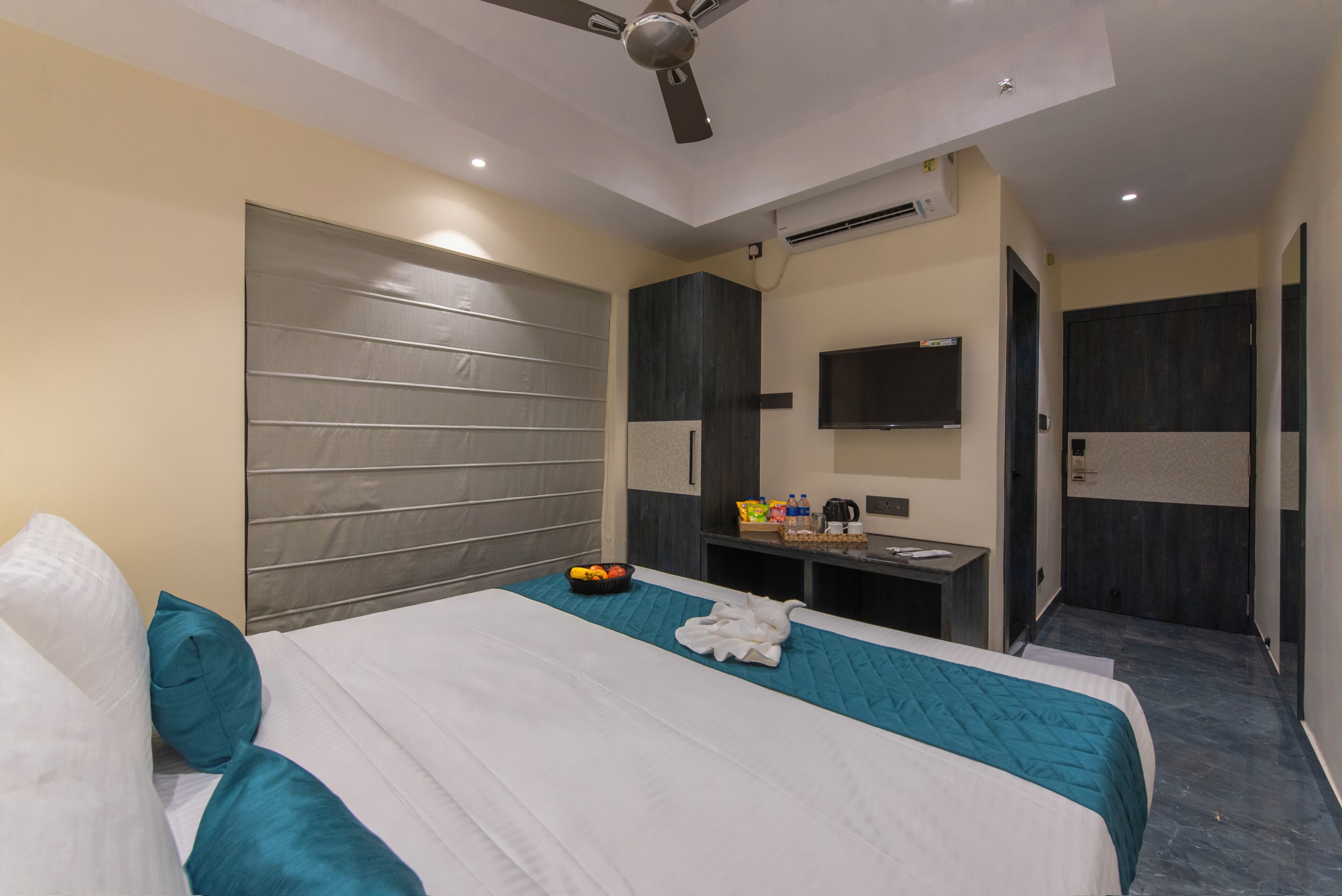 A hotel room with a large bed, a desk, a television, and a wardrobe.