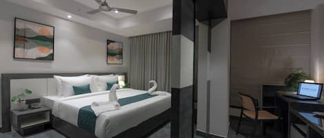 A modern hotel room with a large bed, a desk, and a chair.