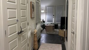 Un couloir avec des portes blanches, une table ronde et un canapé au fond.