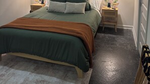 Une chambre à coucher comprenant un lit, deux tables de chevet, une commode, un banc en bois et un mur décoré d’autocollants représentant des feuilles.
