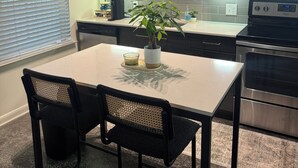 Une cuisine moderne avec des meubles de couleur bois foncé, un four en acier inoxydable et une table à manger avec deux chaises.