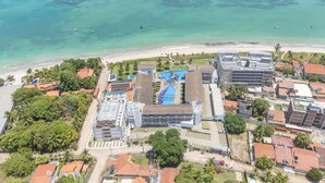 Ein Luftbild eines Küstenresorts mit mehreren Gebäuden, einem Schwimmbad und einem Strand.
