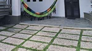Un bâtiment blanc avec une porte noire, un hamac et un escalier.