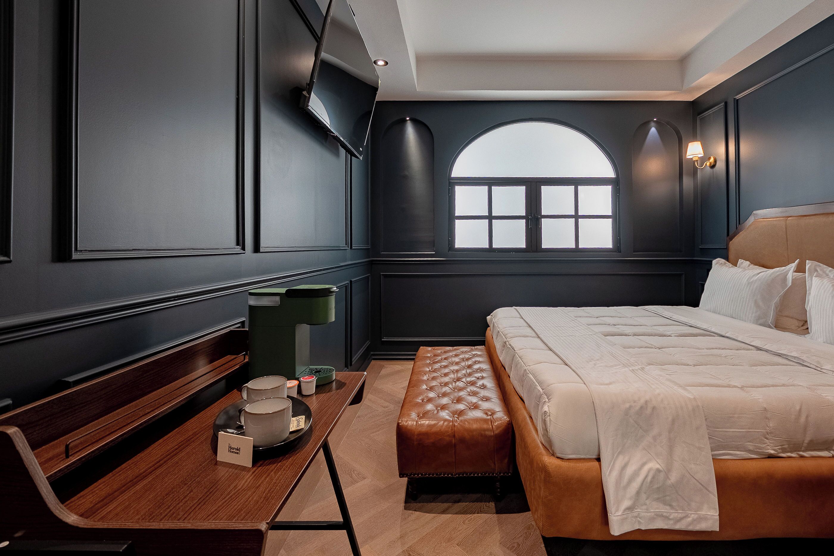 Un dormitorio moderno con una cama grande, una mesita de noche, un banco y una ventana con vistas.