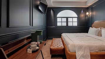 Un dormitorio moderno con una cama grande, una mesita de noche, un banco y una ventana con vistas.