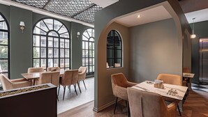 A modern dining area with high ceilings, large windows, and a mix of seating arrangements. - The Midnight Bloom Suite  (Mexico City)