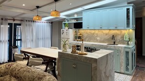 A modern kitchen with light blue cabinets, a marble countertop, and a dining area with a table and chairs. - Casa Corrales by Wynwood House (Andahuaylillas)