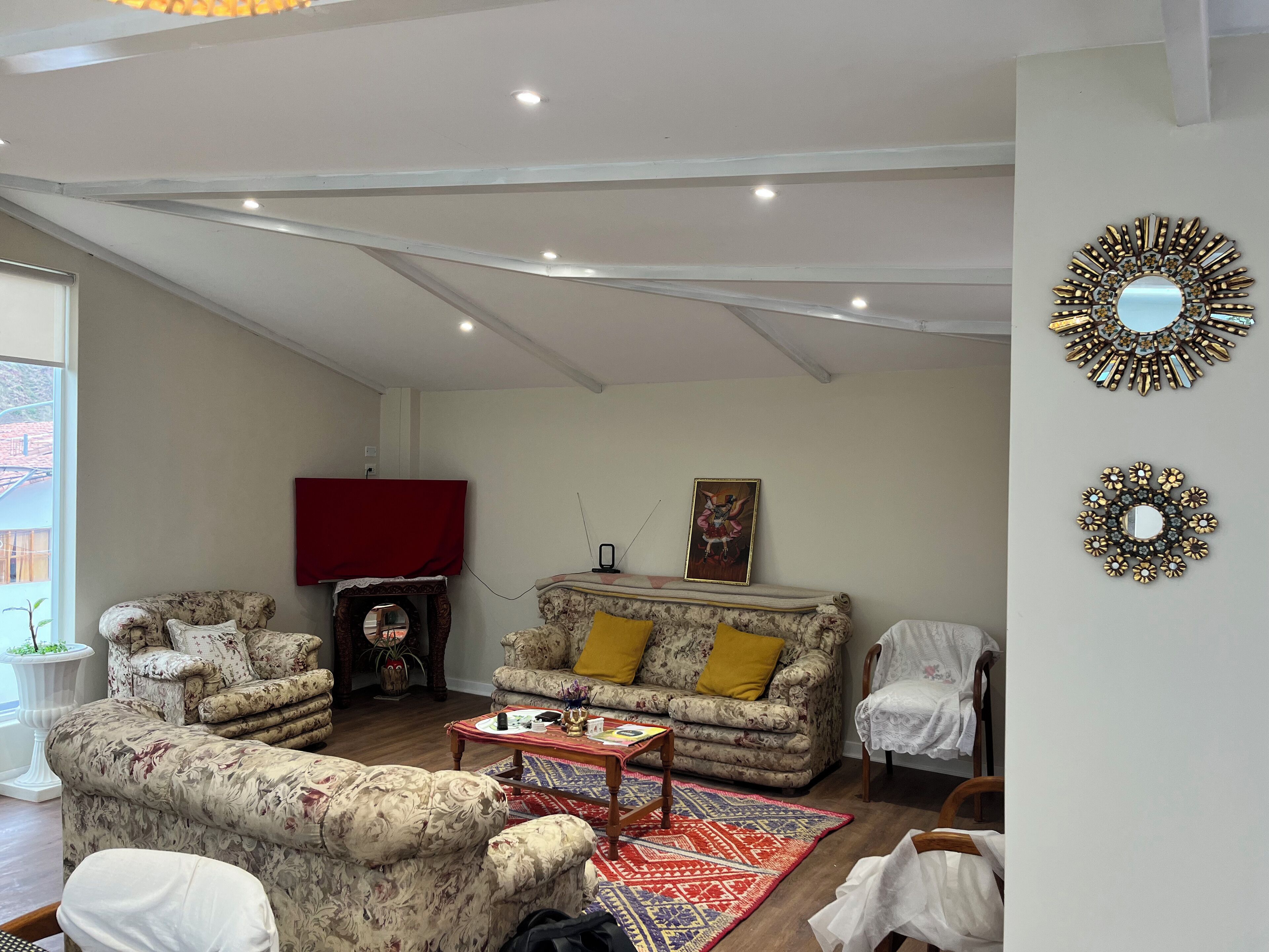 A living room with floral-patterned sofas, a red-covered fireplace, a coffee table, and decorative wall mirrors.