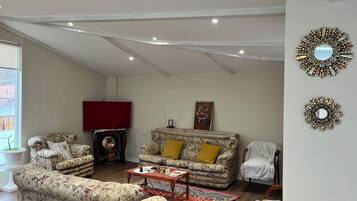 A living room with floral-patterned sofas, a red-covered fireplace, a coffee table, and decorative wall mirrors.