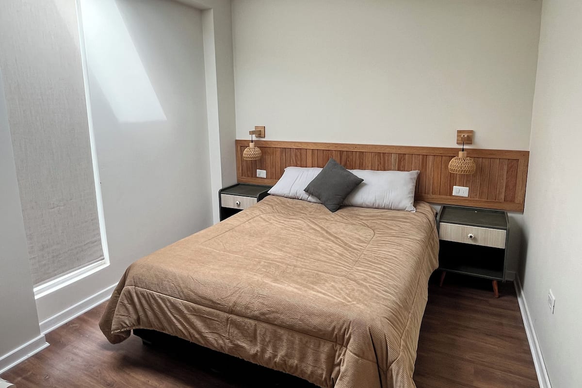 Quarto bem arrumado com uma cama grande, duas mesas de cabeceira e cabeceira de madeira.