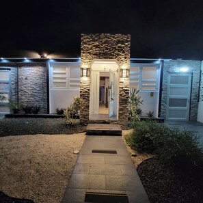 Ein modernes Haus mit Natursteinfassade, einer zentralen Tür und einer Auffahrt zu einer Garage.