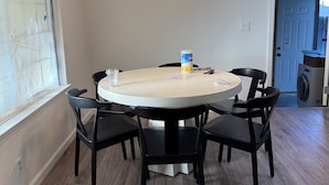 Un comedor con una mesa redonda, sillas negras y una lámpara colgante.