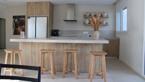 Eine moderne Küche mit Holzelementen, einer zentralen Kochinsel mit Barhocker und einem eingebauten Herd.