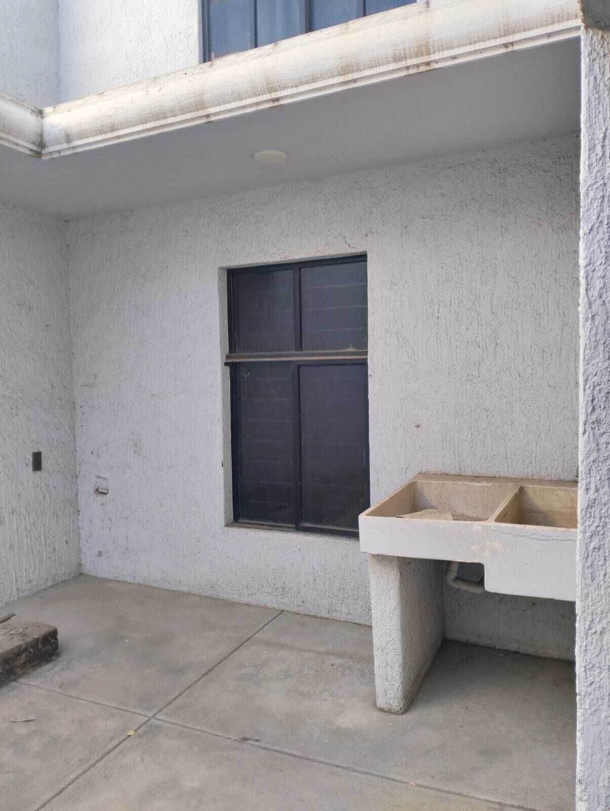 A concrete balcony with a window and a concrete bench.