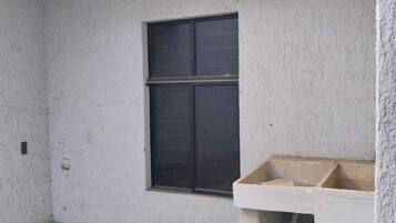 A concrete balcony with a window and a concrete bench.