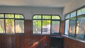 Una habitación con piso a cuadros, ventanas amplias con rejas y un techo alto.