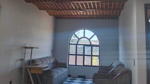 Una habitación con suelo a cuadros, dos ventanas arqueadas, un banco y una escalera.