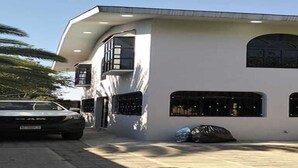Un edificio moderno de dos pisos con un coche estacionado adelante.