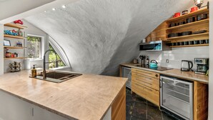 A kitchen with a stone arch, wooden shelves, a sink, and a refrigerator. - The Iconic Vail Dome, 7 Bedrooms in Vail (Vail)
