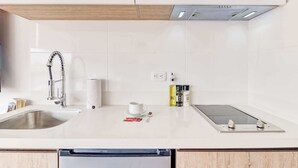 Une cuisine moderne dotée d’un évier en acier inoxydable, d’une cuisinière encastrée et d’un plafond en bois.