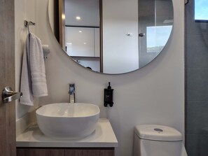 Une salle de bain moderne avec un lavabo blanc, des toilettes et un grand miroir.