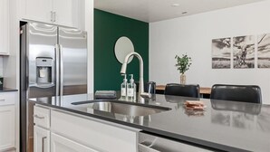 A modern kitchen with a stainless steel refrigerator, a sink, and a dining area with a table and chairs. - Near Eagle Island | Pool | 2 King Beds | Parking | Smart TV (Eagle)
