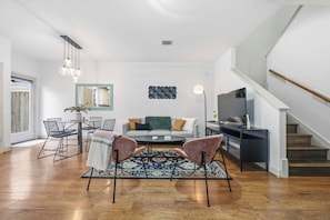 Un salon moderne avec un canapé, des fauteuils, une table basse et un téléviseur.