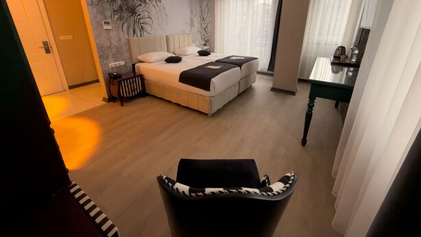 A bedroom with a large bed, a desk, a chair, and a mural on the wall. - steelbutikotel (Kocasinan)