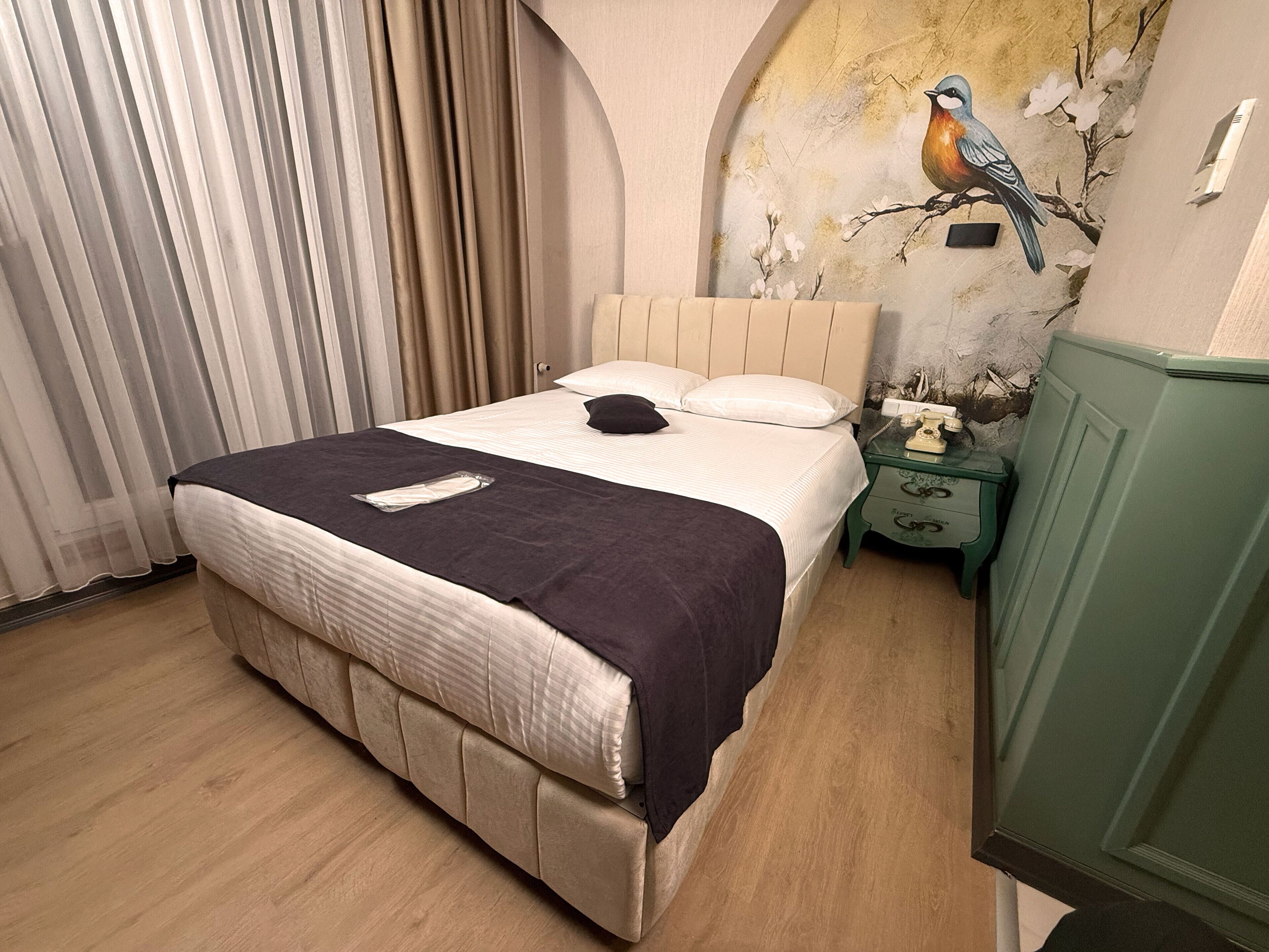 Un dormitorio con cama, mesita de noche, teléfono y un mural en la pared.