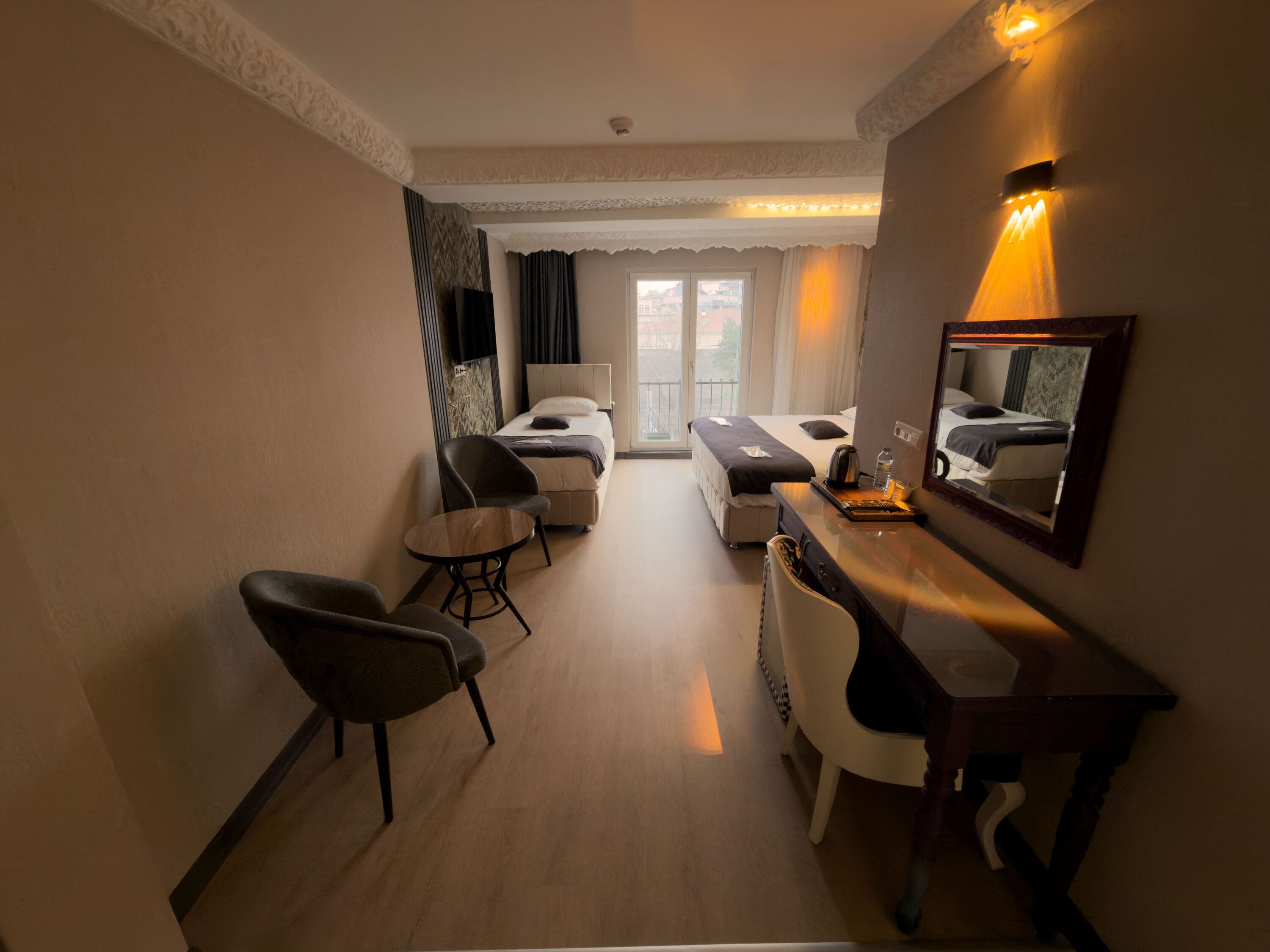 Une chambre d’hôtel comprenant un lit, un bureau, une chaise, une petite table et un miroir.