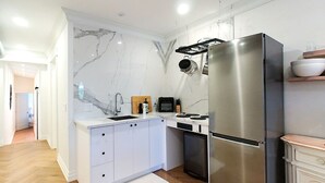 A modern kitchen with a marble backsplash, stainless steel appliances, and white cabinetry. - Chic Retreat Downtown Meaford 2 min to Georgian bay and ~20 min to ski hills (Meaford)