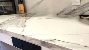 A kitchen counter with a marble backsplash and a modern dishwasher. - Chic Retreat Downtown Meaford 2 min to Georgian bay and ~20 min to ski hills (Meaford)