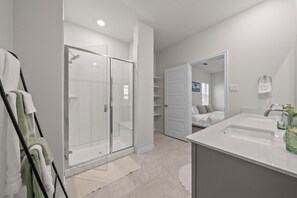 A modern bathroom with a glass-enclosed shower, a large sink, and a walk-in closet. - Luxurious 4-Bed Home in Aubrey TX (Aubrey)