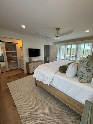 A bedroom with a bed, a TV, a wardrobe, and a window with a view.