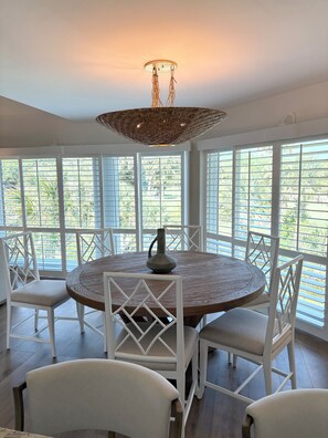 A dining area with a round table, white chairs, and a hanging light fixture. - Charming 2-bedroom villa on Beautiful Seabrook Island (Johns Island)