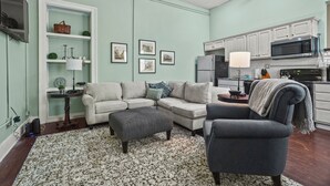 A living room with a sectional sofa, a gray armchair, and a patterned rug. - Local Discounts-Charming View of Downtown Newark (Newark)