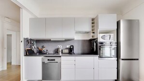 A modern kitchen with white cabinets, a stainless steel refrigerator, a dishwasher, and a coffee maker. - Top floor Saint Germain Terrace Apartmrent (Paris)