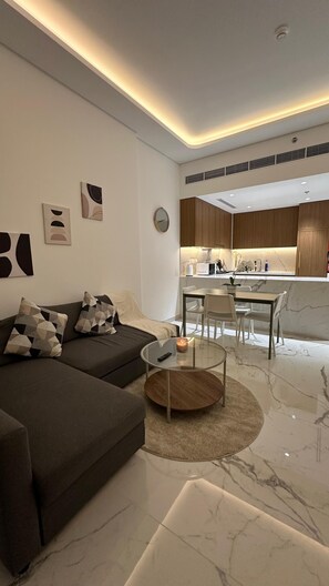 A modern living room with a dark sofa, a glass coffee table, and a marble floor. - Cozy 1-bedroom apartment with AC in awesome Dubai (Dubai)