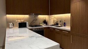 Una cocina moderna con encimeras de mármol, armarios de madera y electrodomésticos integrados.