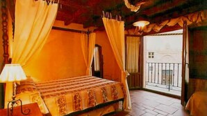 Une chambre à coucher avec un lit, des rideaux, une table de chevet et une vue sur l’extérieur.