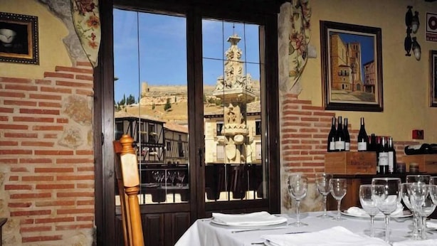 Un restaurant offrant une vue sur un bâtiment historique, un mur de briques et une table dressée pour le dîner.