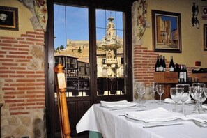 Ein Restaurant mit Blick auf ein historisches Gebäude, eine Ziegelwand und einen gedeckten Tisch.