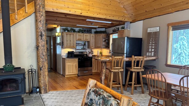 Een gezellige keuken met houten kastjes, een zwarte koelkast en een eethoek met houten stoelen.