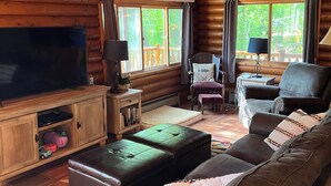 A log cabin interior with a wooden ceiling, a large flat-screen TV, leather furniture, and deer taxidermy. - Wisconsin River Getaway. Large yard and shoreline. Pet friendly. (Merrill)