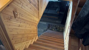 A wooden staircase with a view of a living area. - Wisconsin River Getaway. Large yard and shoreline. Pet friendly. (Merrill)