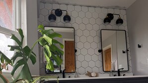 Et moderne badeværelse med et hvidt badekar, mørke skabe og en backsplash med sekskantede fliser.