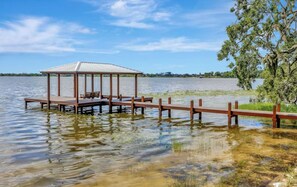 A wooden dock with a gazebo, benches, and a swing, extending into a calm lake.