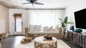 Una sala de estar moderna con un sofá, una mesita redonda y un televisor sobre un mueble.