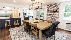 Een moderne keuken met een centraal eiland, een houten eettafel en barkrukken.