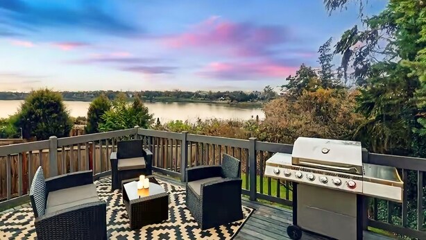 Een terras met buitenmeubels en een barbecue met uitzicht op een meer.